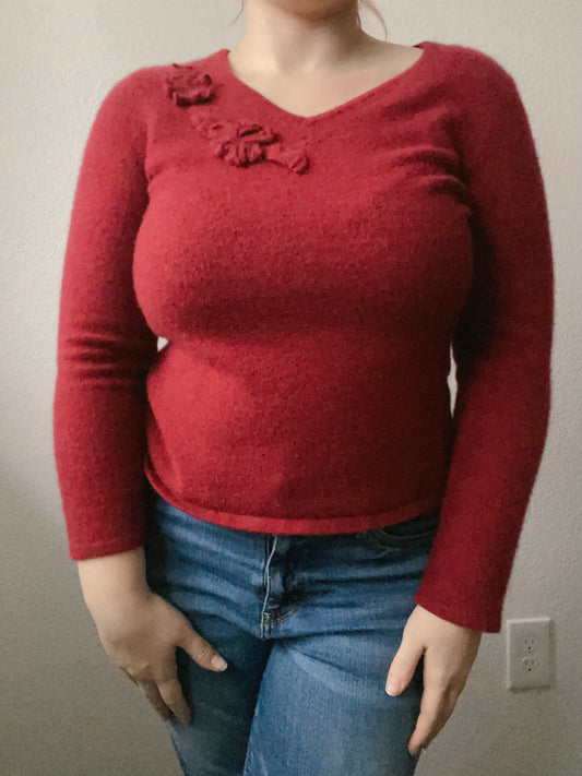 Person wearing a red sweater with floral details and blue jeans against a plain background Cashmere Floral Top | From the Rack | Grace Thrifts