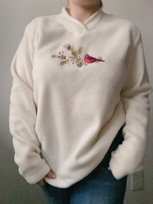 White sweater with floral and bird embroidery worn by a person against a neutral background Cardinal Fleece Sweater | From the Rack | Grace Thrifts
