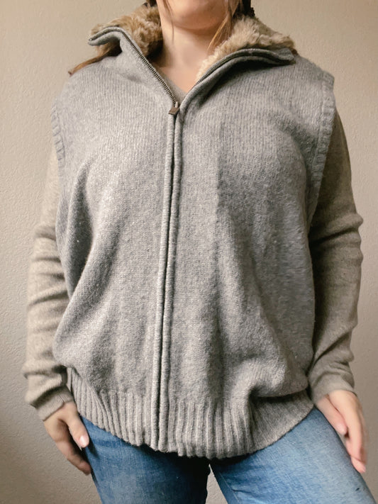 Person wearing a gray sweater against a plain wall Faux Fur Lined Vest | From the Rack | Grace Thrifts