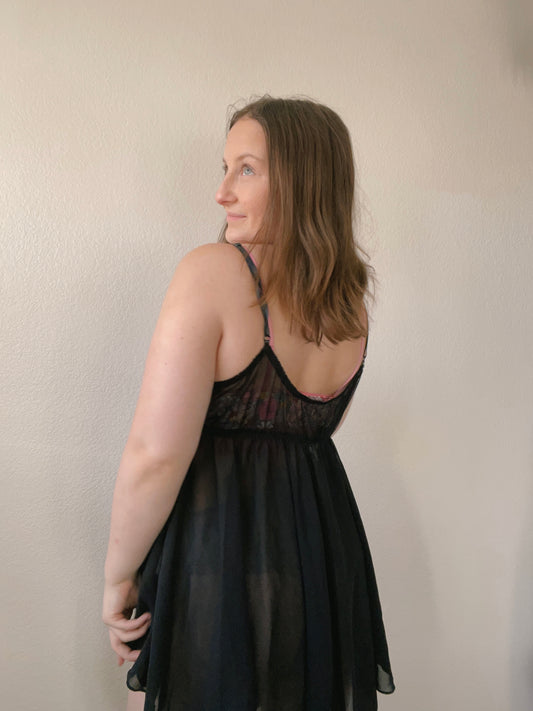 Woman wearing a black lace nightgown against a plain background