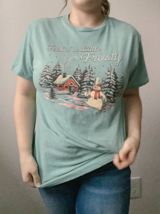 Person wearing a green t-shirt and blue jeans against a plain background Feelin' A Little Frosty Graphic Tee | From the Rack | Grace Thrifts