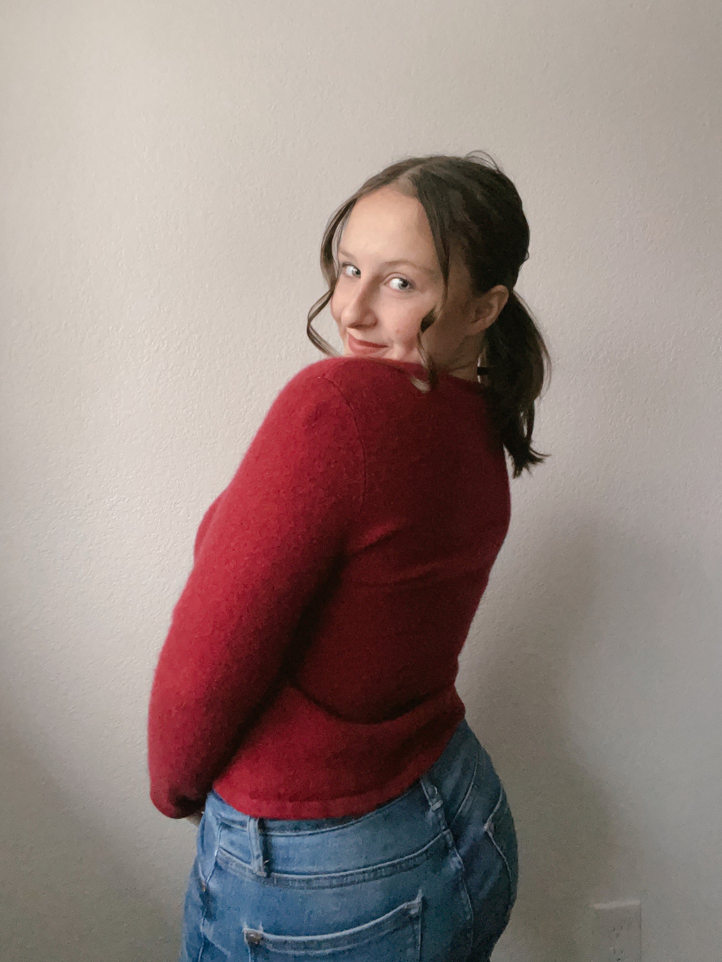 Person wearing a red sweater with floral details and blue jeans against a plain background Cashmere Floral Top | From the Rack | Grace Thrifts