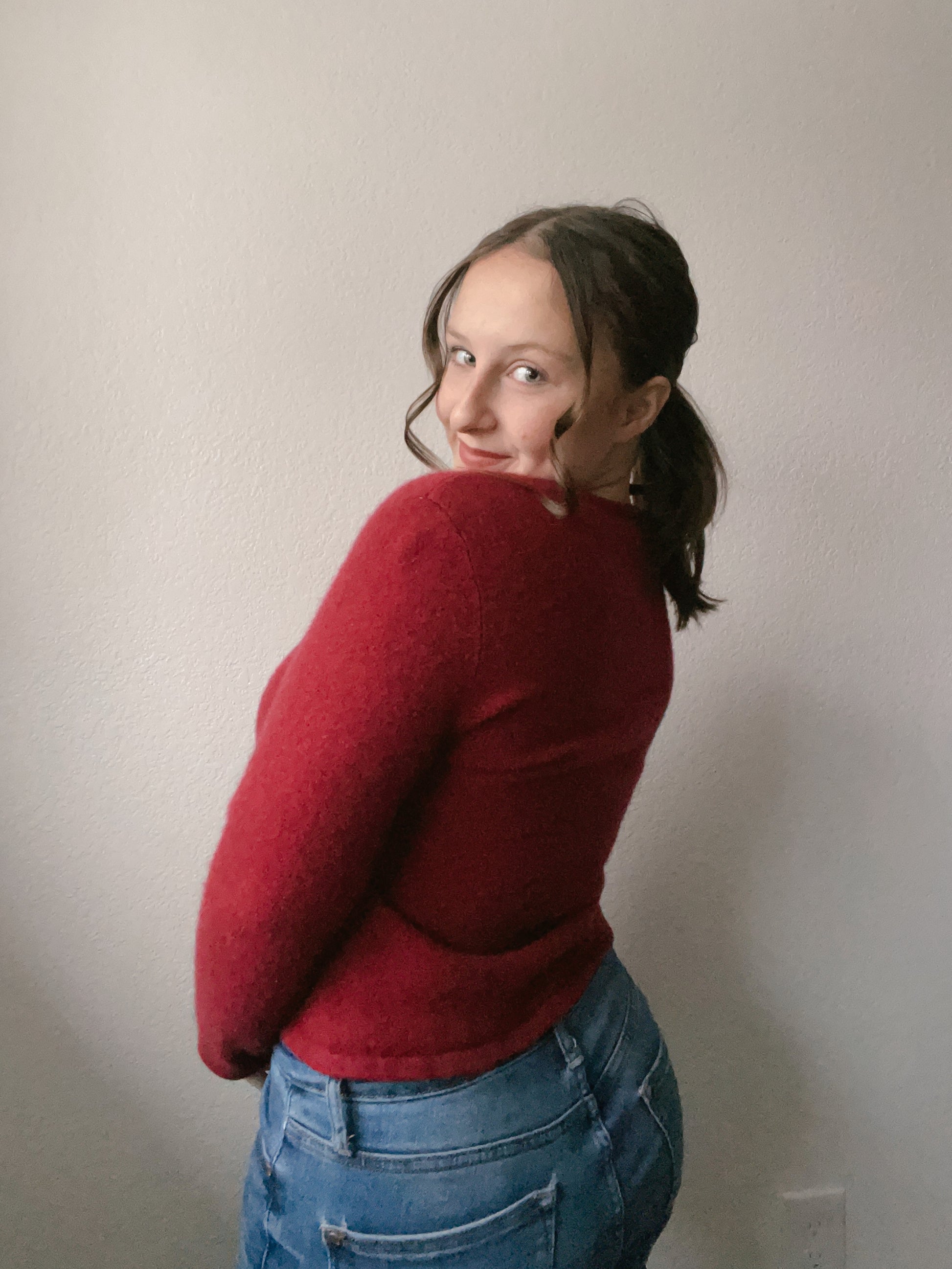 Person wearing a red sweater with floral details and blue jeans against a plain background Cashmere Floral Top | From the Rack | Grace Thrifts