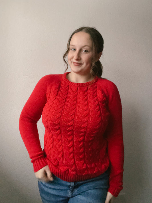 Person wearing a red cable knit sweater against a plain background Red Classic Cable Knit Sweater | From the Rack | Grace Thrifts