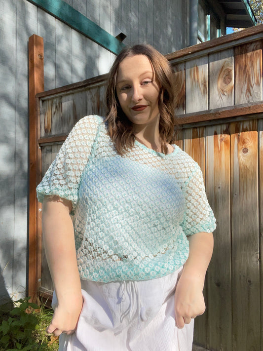 Woman wearing a light blue and white patterned top outdoors against a wooden fence | Grace Thrifts