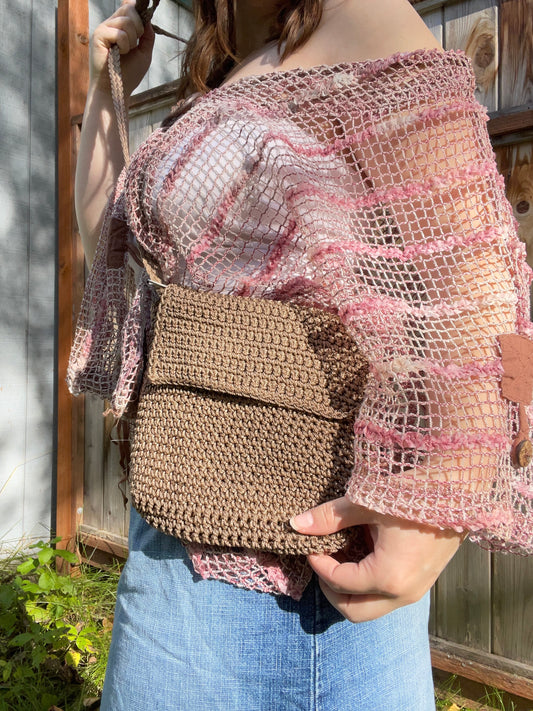Person holding a brown woven bag with a pink and white patterned top.