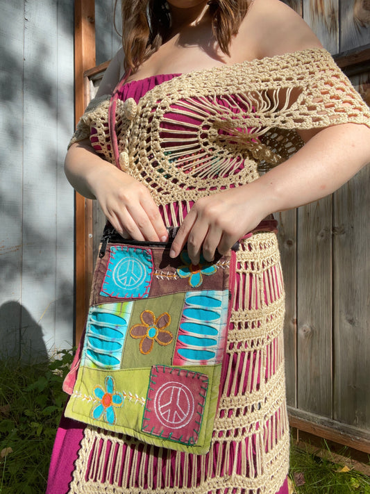 Person wearing a colorful crochet top and skirt with a patchwork purse.