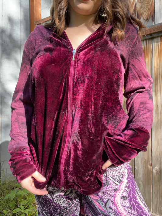 Woman wearing a maroon velvet jacket standing in front of a wooden fence | Grace Thrifts