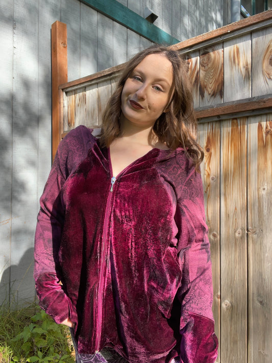 Woman wearing a maroon velvet jacket standing in front of a wooden fence | Grace Thrifts