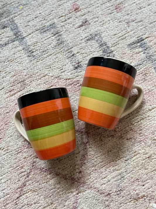 Two striped ceramic mugs on a textured surface