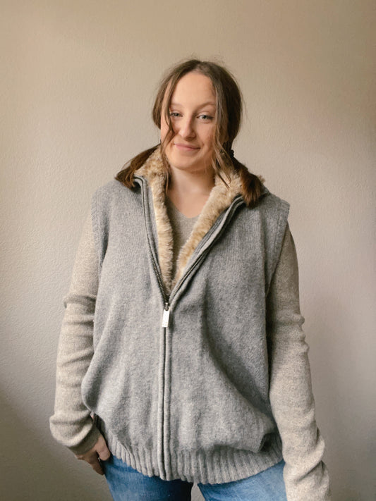 Person wearing a gray sweater  against a plain wall Faux Fur Lined Vest | From the Rack | Grace Thrifts