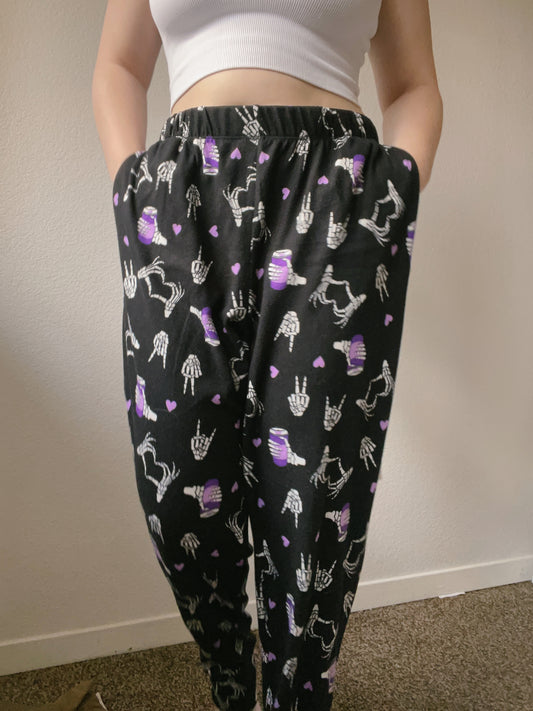 Person wearing black pants with skeleton and heart pattern against a plain background